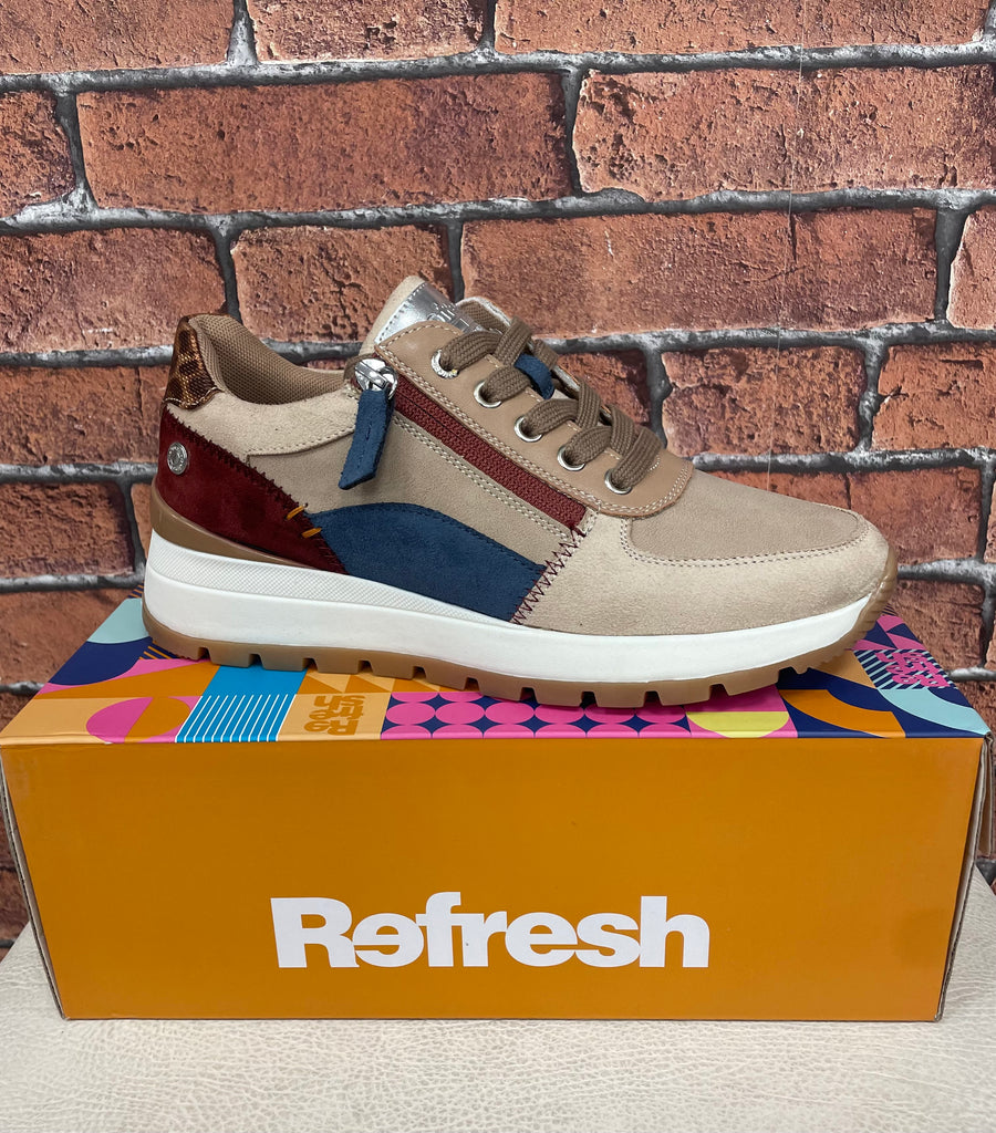 Multicolored sneaker on a colorful box with 'Refresh' branding against a brick wall.