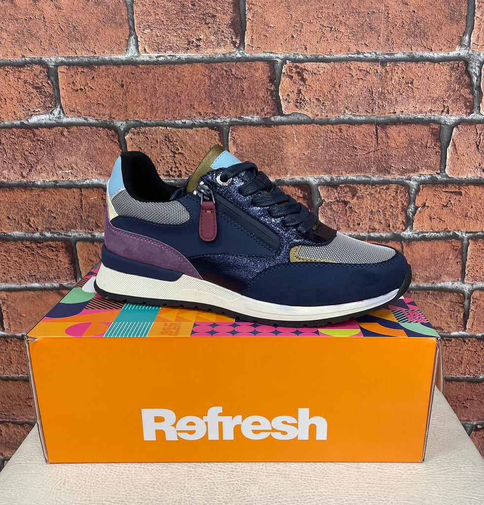 Navy and gray sneaker on a colorful box with 'Refresh' branding against a brick wall.